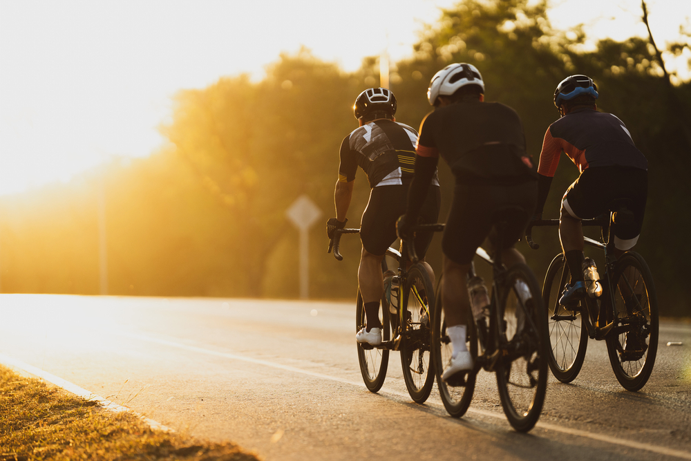 grupo de ciclistas con puesta de sol de fondo